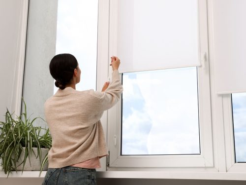 Australian woman using white roller window blinds after successful measurements.