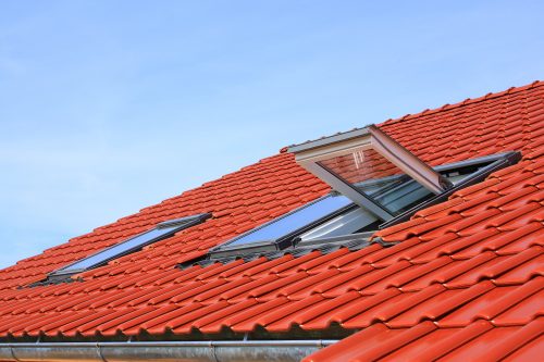 An opened roof window on a red tile roof