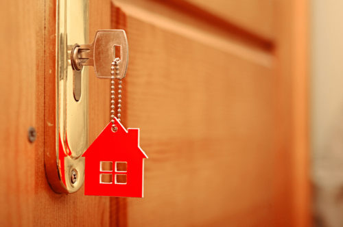 A key with a house keychain in a door lock