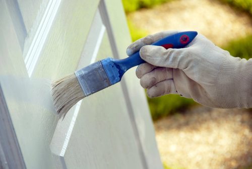 A homeowner painting a wooden door in their home