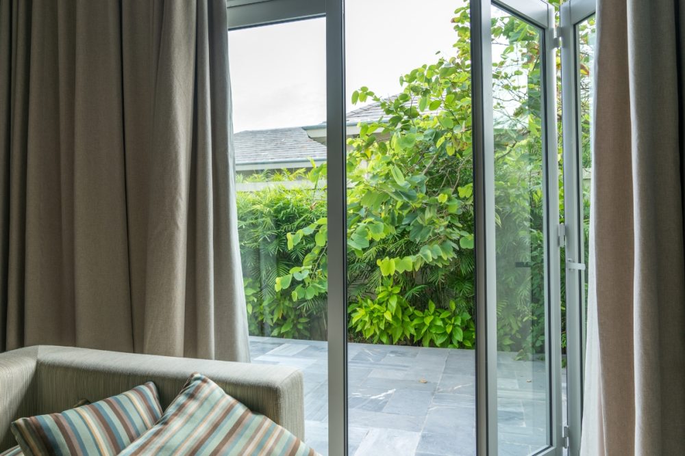 Bi-fold windows open with a view looking out onto the greenery of a backyard.