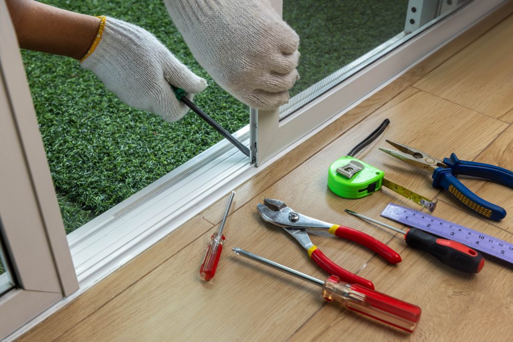 Close up of someone fixing sliding door rollers with a screwdriver.